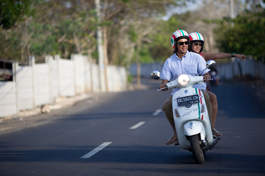 Fotografer prewedding Jakarta mengambil foto pasangan naik vespa di jalan dengan konsep outdoor romantis