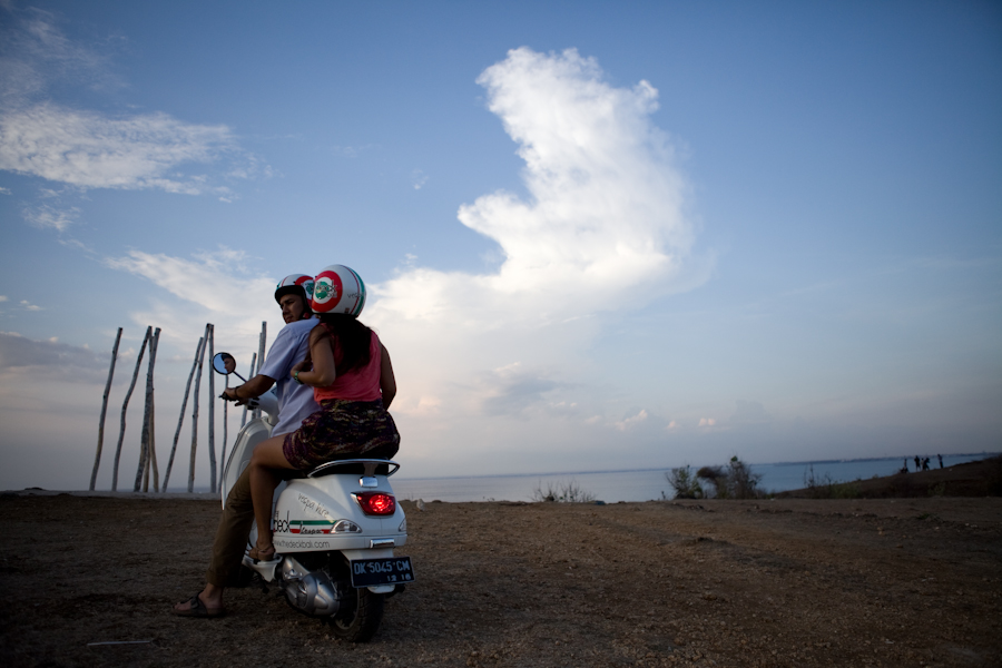 Pasangan prewedding mengendarai Vespa klasik di tepi pantai saat senja oleh fotografer prewedding Jakarta