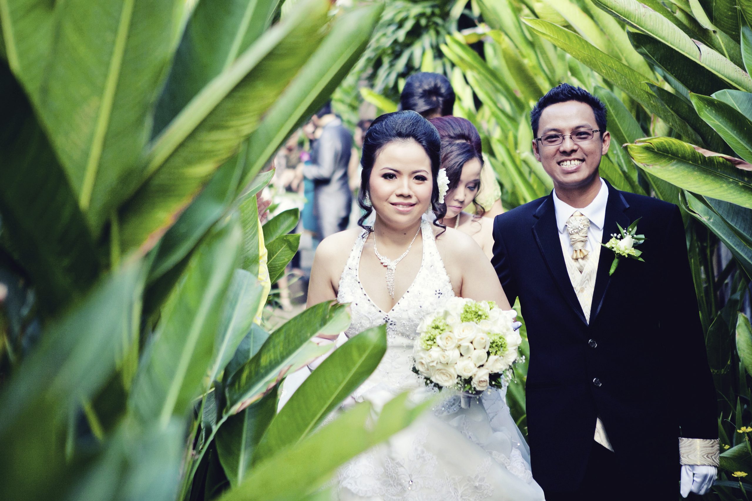 Pasangan pengantin berjalan di taman tropis untuk sesi foto prewedding di Jakarta bersama fotografer prewedding profesional.